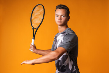 Portrait of a young man tennis player on orange background
