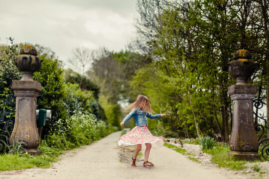 Little girl in flower dress twirling at the start of an entranceway