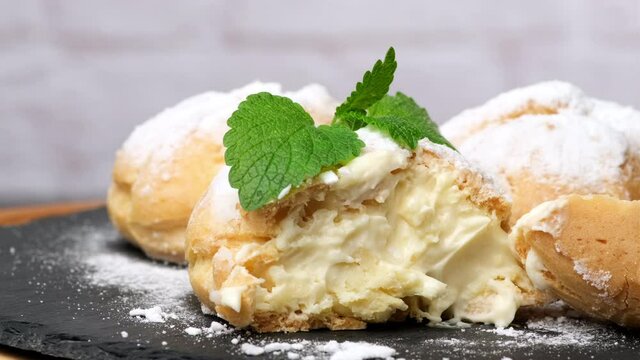 half a baked custard eclair sprinkled with icing sugar, close up