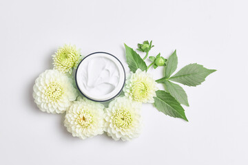 Fototapeta na wymiar spa concept or template for salon treatment invitation. florals compositions made white flowers and skincare cream. simple flat lay, close-up