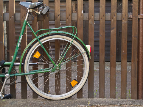 backwheel of an old bicycle leaning against a fence