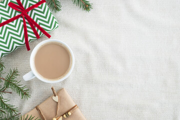 Christmas and winter composition. Cup of coffee, gift boxes and branch fir-tree on pastel beige plaid. Top view, flat lay, copy space