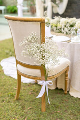 a baby breath flower tied on a gold dining chair as a decoration