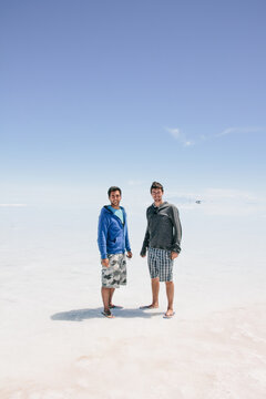 Two young male friends on salt flat on adventure travel - Uyuni, Bolivia, South America