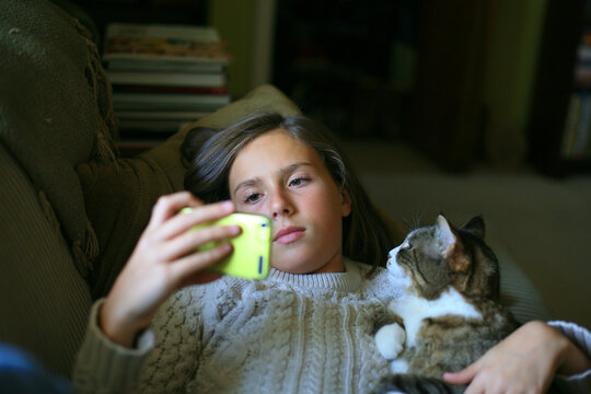 Girl Relaxing With Her Mobile Device And Pet Cat