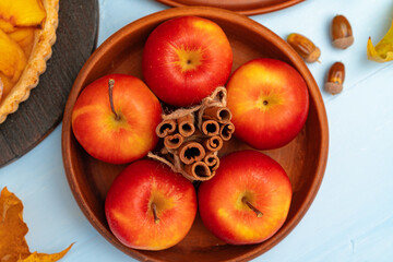 Top view of red apples and cinnamon sticks on clay plate