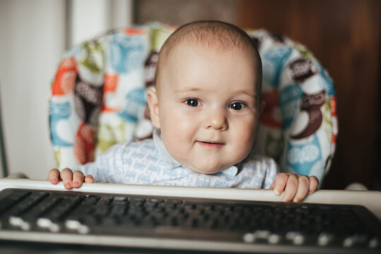 portrait of a cute baby boy sitting and playing with a keyboard