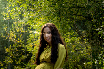 Pregnant woman in yellow dress in nature