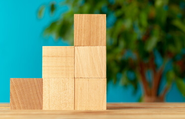 Wooden blocks on desk against blurred plant background