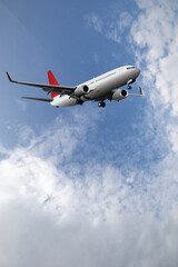 Commercial passenger plane with landing gear down set against a blue cloudy daytime sky