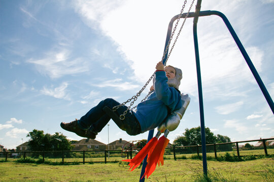 Boy with toy rocket pack on a swing