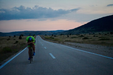 Obraz premium triathlon athlete riding bike at night