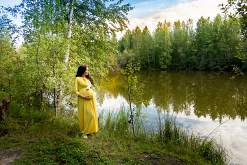 Pregnant woman in yellow dress in nature