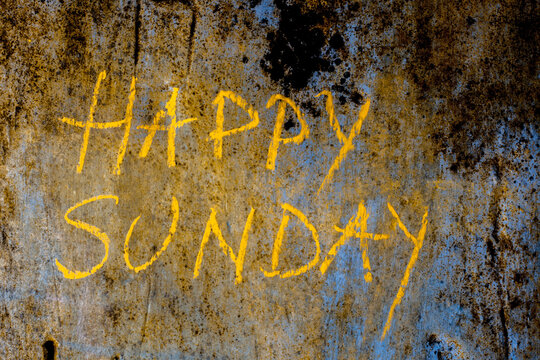 Happy Sunday wrote on the rough wall with yellow-colored chalk, close up horizontal shot.