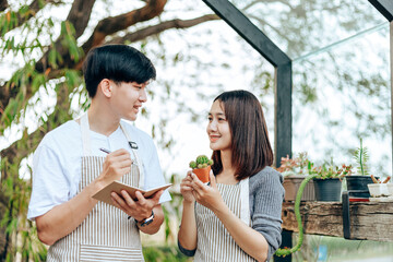 Women hold cactus and a man writing note in a book. Love couple enjoy hobby with garden cactus.