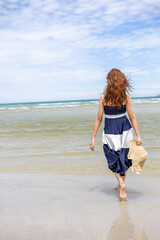 Woman barefoot walking on summer along wave of sea water and sand on the beach.