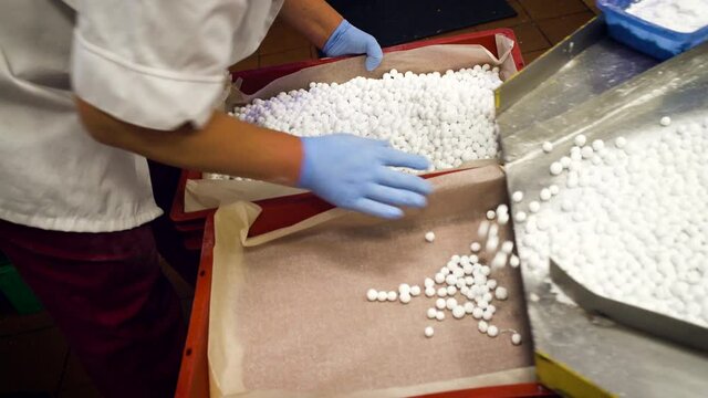 Closeup of worker's hands in gloves sorting sugar cranberry in boxes after conveyor production.
