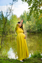 Pregnant woman in yellow dress in nature