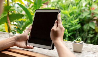 Close up of man using cell taplet, sending massages on the garden.having sunbath. taplet with black screen,texting,video calls,