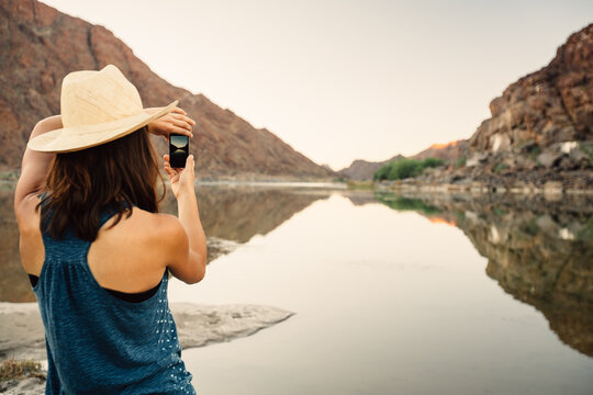 Woman taking a photo of a lake or river with a mobile phone