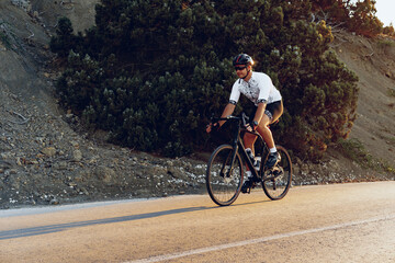 Naklejka premium Professional cyclist on a mountain road at sunrise
