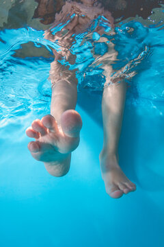 Kid's feet in the pool underwater