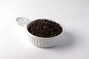 Fototapeta na wymiar Black pepper in a white ceramic cup on a white background