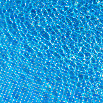 Background texture of blue water in the swimming pool.