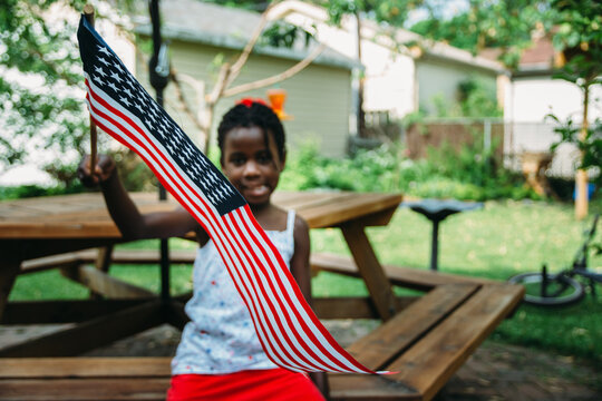 Cute African-American Girl in USA Flag Colors Themed Outfit Holding A Flag