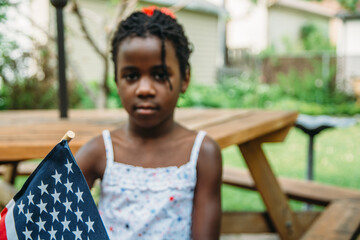 Cute African-American Girl in USA Flag Colors Themed Outfit Holding A Flag