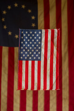 A small American flag in front of a replica of the Betsy Ross flag