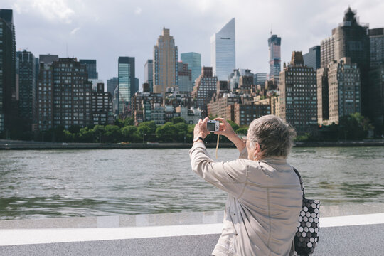Woman Senior Citizen with old Instamatic Digital Camera Technology Taking Photos of New York City Skyline