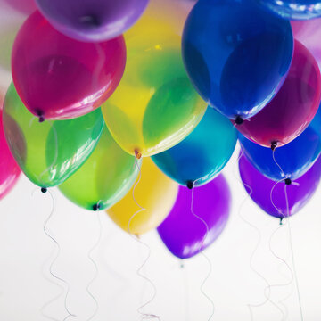 Close-up of helium colourful ballons flying in sunny room