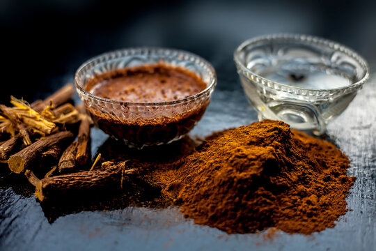 Close up shot of fresh raw revand chini roots and its paste in a glass bowl along with some raw powder on a wooden black surface.
