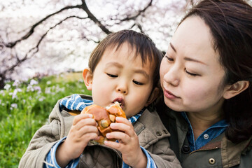 Asian toddler, eating bread with his mother