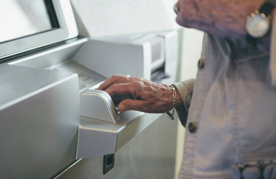 Woman Senior Citizen Entering Pin Number on Keypad of Bank ATM machine Technology
