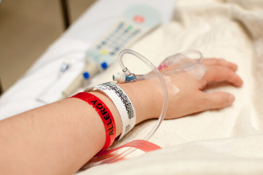 a hand with an iv and hospital bracelets