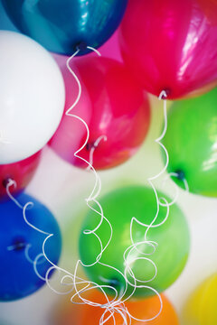 Colourful balloons and curly strings seen from below