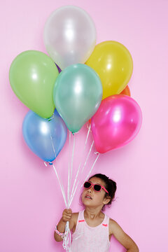 Beautiful and funny little girl holding colorful balloons