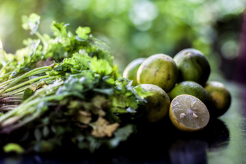 Face mask for blackhead and dry skin on a surface consisting of some coriander leaves and fresh lemon juice. Shot of fresh parsley leaves and lemons for blackhead removal face mask.