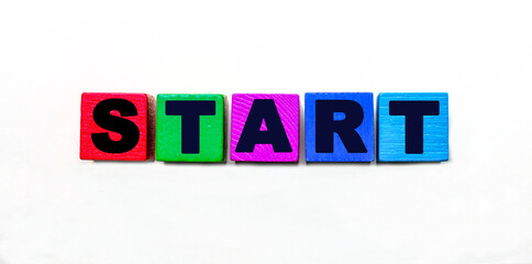 The word START is written on multi-colored wooden cubes on a light background.