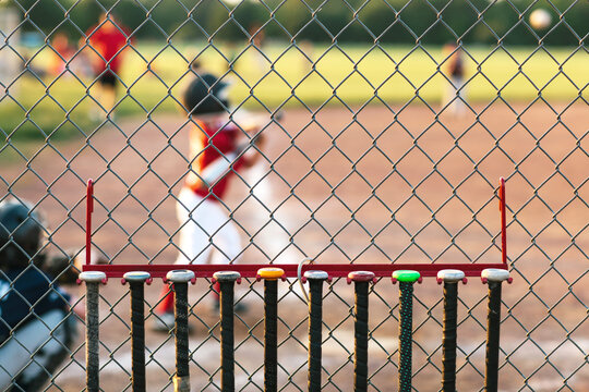 Row Of Baseball Bats Hanging From A Fence During A Game