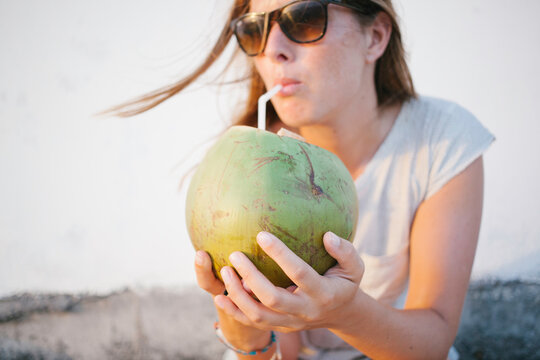 Handsome young woman drinking fresh coconut water.