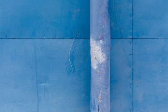Blue drain pipe and painted metal wall