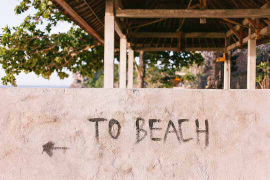 A wall at the ocean with directions to the beach.