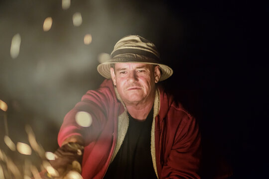 Mature man stoking a campfire
