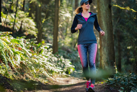 Mature woman running on trails in forest in Portland, Oregon