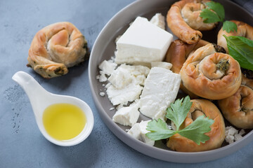 Close-up of baked greek spirals stuffed with spinach and feta cheese, selective focus, studio shot on a grey concrete surface