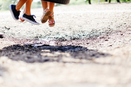 Kids feet hanging from tire swing in summer