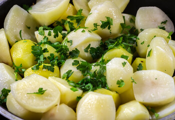 Close-up of potatoes with herbs in a pan during frying.